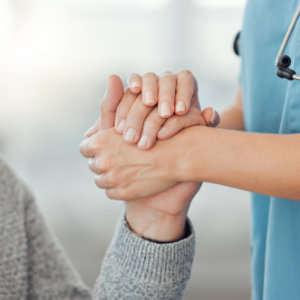 Intensivpflegerin nimmt Hand des Pflegebedürftigen