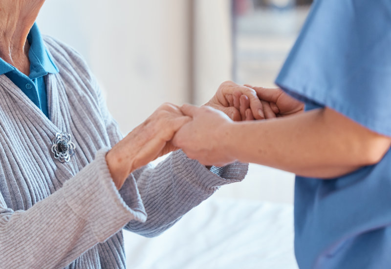 Eine Intensivpflegerin kümmert sich liebevoll um eine pflegebedürftige Seniorin