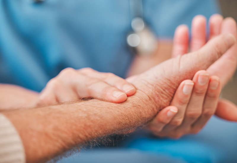 Intensivpflegerin kontrolliert den Puls eines Mannes